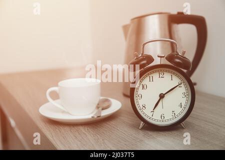 Morning Time with bell clock and Coffee or Tea hot drinks on wooden table. Stock Photo