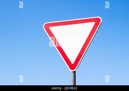 Road sign "Give way" on a blue sky background with mockup and copyspace Stock Photo