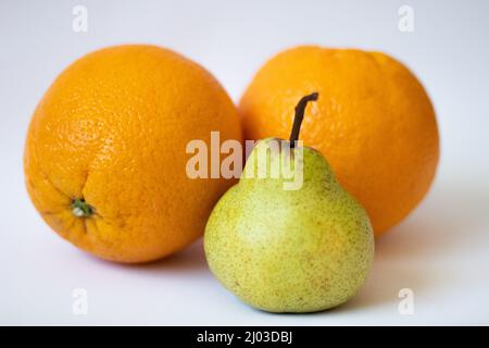 One pear and two oranges on a white isolated background Stock Photo