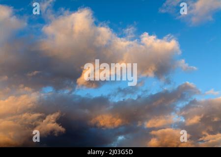 Colourful soft wispy orange clouds against a blue winters sky Stock Photo