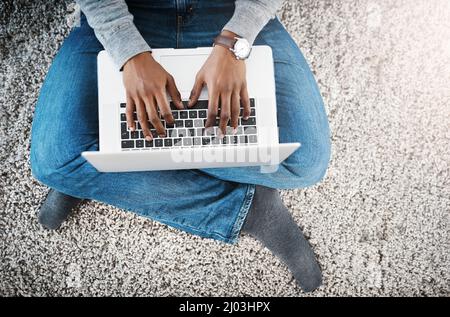 Connect to whatever keeps you relaxed. Shot of a happy young man using a laptop while relaxing at home. Stock Photo