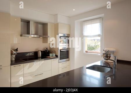 Modern kitchen detail with large dark island with stools. Stainless steel sink and bright window. Stock Photo