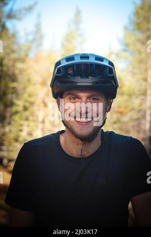 recreational cyclist smiles with satisfaction after a challenging trail in the mud. Candid portrait of a young athlete with a real smile and mud on hi Stock Photo