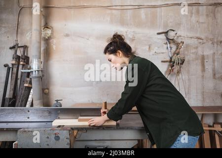Side view of woodworker using jointer machine in workshop Stock Photo