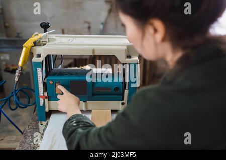 Blurred furniture designer using bench thicknesser near wooden plank in workshop Stock Photo