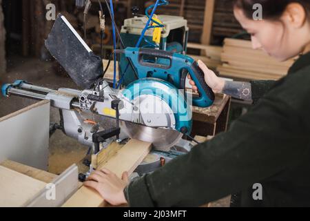 Blurred woodworker using miter saw in workshop Stock Photo