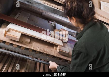 High angle view of tattooed furniture designer polishing wooden plank in workshop Stock Photo