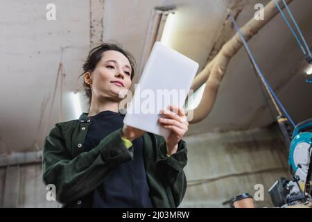 Low angle view of brunette carpenter using digital tablet in workshop Stock Photo