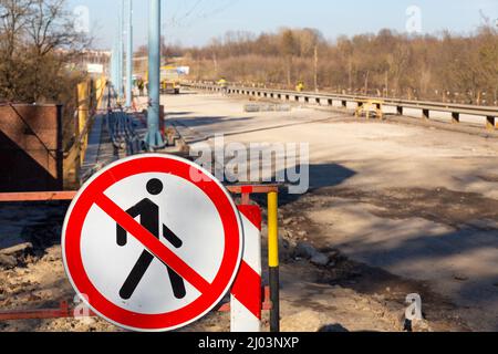 Barrier blocking sidewalk and sign with picture of crossed-out man prohibiting the passage of pedestrians, because the bridge is under repair or it is Stock Photo