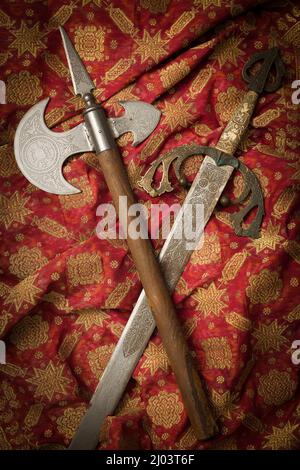 Brass conquistador sword. This is a Spanish 19th century Toledo sword as used by medieval knights.  Medieval battle axe with wooden handle and steel b Stock Photo