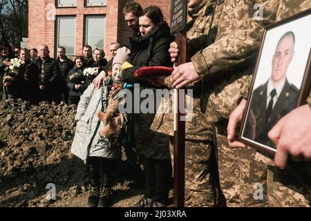 The daughter of Rostyslav Romanchuk, eight-year-old Viktoria, cries as her father's casket is lowered into his grave at the Lychakivske Cemetery in Lviv. Romanchuk was one of 35 killed in an airstrike on a military base near the Polish border. Mourners gathered in Lychakivske cemetery in Lviv, for the burial of four Ukrainian soldiers; Oleh Yaschyshyn, Sergiy Melnyk, Rostyslav Romanchuk, and Kyrylo Vyshyvany who were killed by a Russian airstrike on the International Center for Peacekeeping and Security, a military base in Yavoriv near the Polish border earlier in the week. Stock Photo