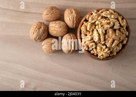 Bowl of walnuts and whole walnut kernels on wooden background,top view Stock Photo