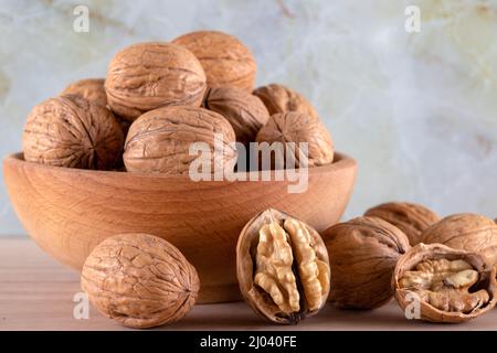 Walnut kernels and whole walnuts on wooden background,front view Stock Photo