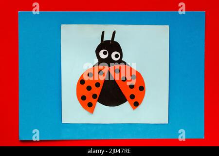 Top view of papercraft ladybug made by child on multicolor sheets background Stock Photo