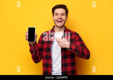 Cheerful guy pointing at empty smart phone screen Stock Photo
