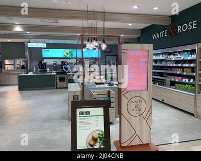 Waite and Rose staff at Waitrose Rushden Northamptonshire UK shop counter staff mask masks sign signs waite and rose vegan menu shelving art Stock Photo