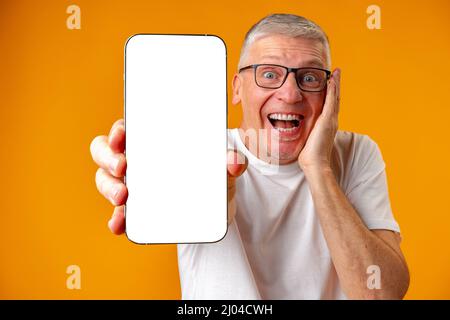 Photo of senior surprised man point finger at smartphone over yellow background Stock Photo