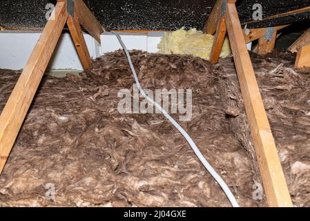 Electric cable in a corrugated conduit on the roof trusses, located in the attic of the house. Stock Photo