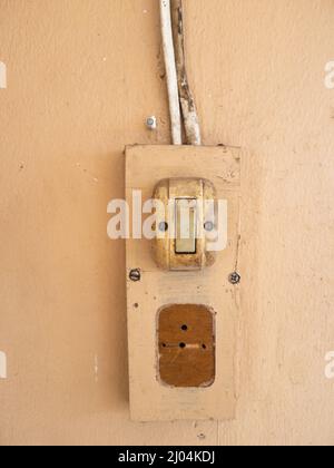 The vintage electric switch for the light bulb on the concrete wall of the old house. front view with the copy space. Stock Photo