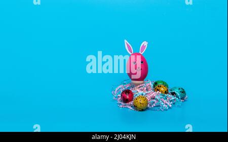 red Easter egg with ears and colored quail eggs Stock Photo