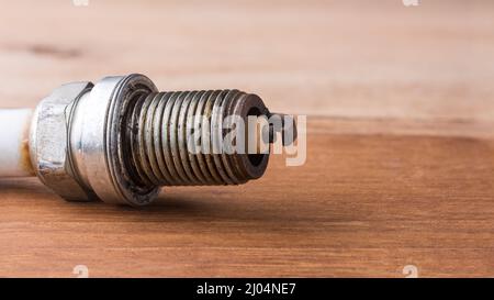 used worn spark plug in shallow depth of field on a table top, closeup macro with copy space Stock Photo
