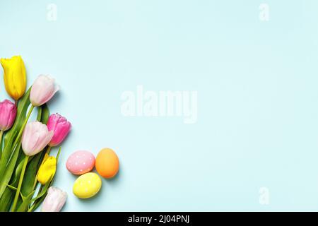 Easter composition. Eggs and flowers tulips on a blue background. Stock Photo