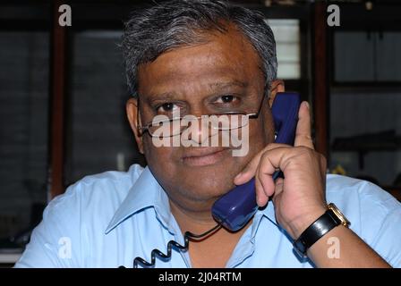 Mumbai; Maharashtra; India- Asia; Dec. 09; 20096 - Portrait of mid age handsome  Indian business man talking on mobile phone Stock Photo