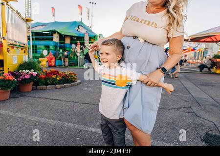 Four year old Caucasian boy smiles while mom holds his hands Stock Photo