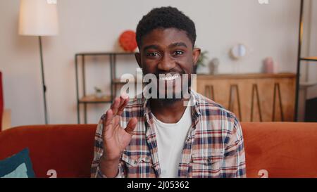 Man sitting on home sofa, looking at camera, making video conference call with friends or parents Stock Photo
