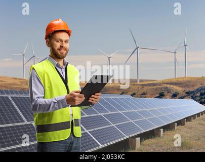 Engineer holding a clipboard on a sustainable solar and wind energy turbine farm Stock Photo