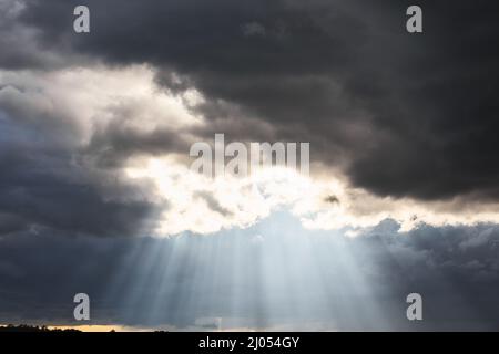 Sunrays shining through an opening in the clouds in a stormy sky Stock Photo
