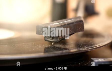 Close-up of the cartridge of an old, ruined turntable reading a 33 rpm vinyl record. Analog sound reproduction in stereo high fidelity Stock Photo