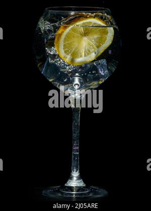 cute lime in a glass with water and splashes on a black background with copy space. Stock Photo