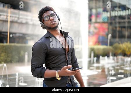 African man with relaxed expression listening to music outdoors Stock Photo