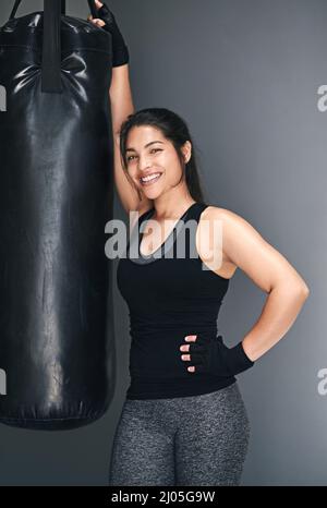 Wanna spot me. Studio shot of a female kickboxer against a gray background. Stock Photo
