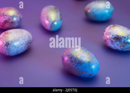 Easter golden eggs with different patterns in neon colors light. Purple very peri color minimalist festive background. Modern trendy Easter. Selective Stock Photo