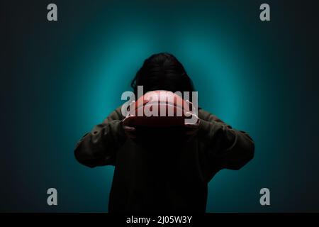 Teenage girl with basketball. Silhouette studio portrait with neon blue colored background. Stock Photo