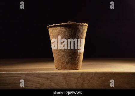 Fibre paper gardening pot. Recycled paper cup for seedlings on wooden table isolated. Stock Photo