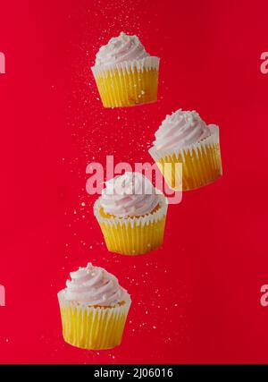 Muffins with pink cream on a red background in a frozen flight. Birthday, holiday invitation, restaurant, confectionery, advertising. Stock Photo