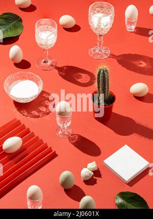 Creative pattern made with champagne, vine glass, easter eggs, cactus, white milk, green leaf, sharp shadows, note space. Minimal easter holiday conce Stock Photo