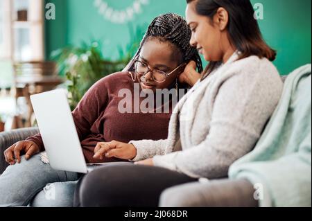 Best friends know the best fashion blogs. Shot of two young women using a laptop on the sofa at home. Stock Photo