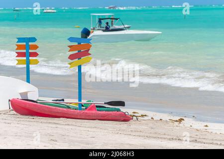 Kayaks on the sand of a beautiful beach and multiple colored signposts. No writing on signposts. Photo taken in Maragogi - AL, Brazil. Stock Photo