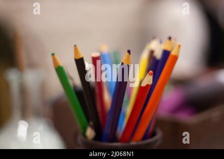 Pencils of different colors. Drawing kit. Purple and red acrylic pencil stands in jar. Background details of artist's work. Stock Photo