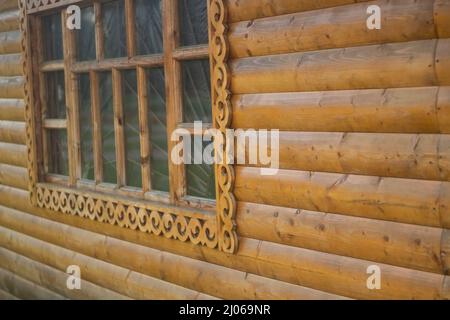 Window in folk style. House in Russia. Window frame carved from wood. Pattern along frame. Details of woodwork. Stock Photo