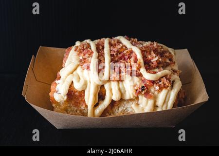 Maple Bacon Frosted cinnamon roll close up on black background Stock Photo