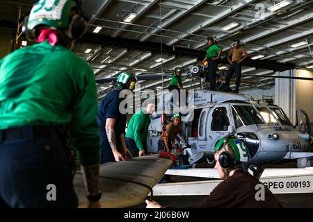 PHILIPPINE SEA (March 15, 2022) Sailors raise a rotor blade to be attached to an MH-60S Sea Hawk helicopter, assigned to the “Chargers” of Helicopter Sea Combat Squadron (HSC) 14, in the hangar bay aboard the Nimitz-class aircraft carrier USS Abraham Lincoln (CVN 72). Abraham Lincoln Strike Group is on a scheduled deployment in the U.S. 7th Fleet area of operations to enhance interoperability through alliances and partnerships while serving as a ready-response force in support of a free and open Indo-Pacific region. (U.S. Navy photo by Mass Communication Specialist Seaman Apprentice Julia Broc Stock Photo