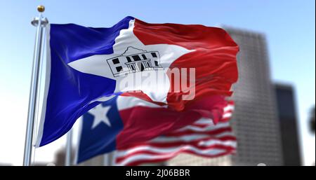 San Antonio city flag waving in the wind with Texas state and United States national flags blurred in background. Black-outlined Alamo in the middle o Stock Photo