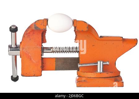 An Egg in the Jaws of an Orange Metal Bench Vice Isolated on a White Background Stock Photo