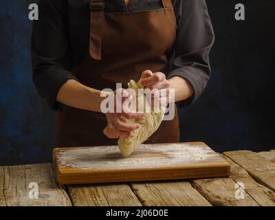 The chef kneads the dough on a wooden table. Close-up. Minimalism. Dough preparation, recipes. Cookbook, food blog, restaurant, hotel, bakery, patisse Stock Photo