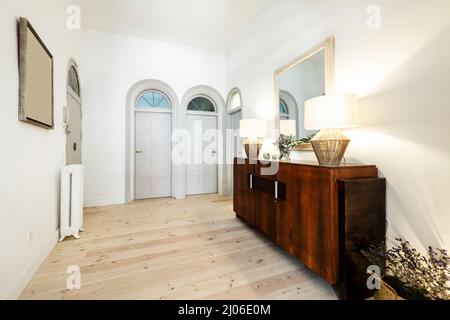 Distributor hall of a house with neo vintage decoration with large wooden lockers, doors with gray semicircular arches and floors of large strips of l Stock Photo